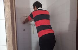 Un padre de familia trabaja para reparar los baños en la Escuela República de El Salvador, barrio Mburicaó de Asunción