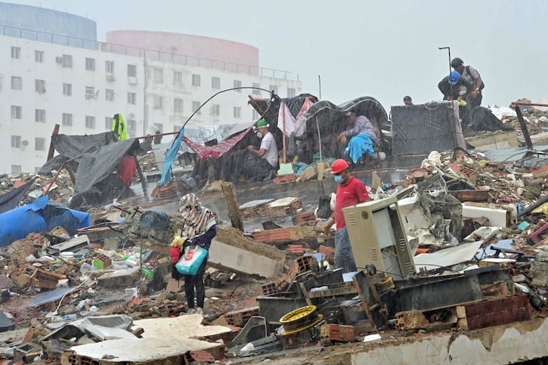 Residentes se resguardan de la lluvia bajo lonas improvisadas entre los escombros de estructuras colapsadas en Caraballeda, estado de La Guaira, Venezuela, el 11 de julio de 2026, tras los dos terremotos que azotaron la región.