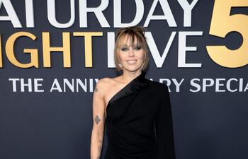 ¡Deslumbrante! Miley Cyrus llegando al evento SNL50: The Anniversary Special. La artista lució un vestido con cuello de esmoquin y una falda asimétrica.
