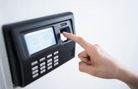 Dedo índice de una persona marcando su asistencia en un dispositivo de control biométrico.