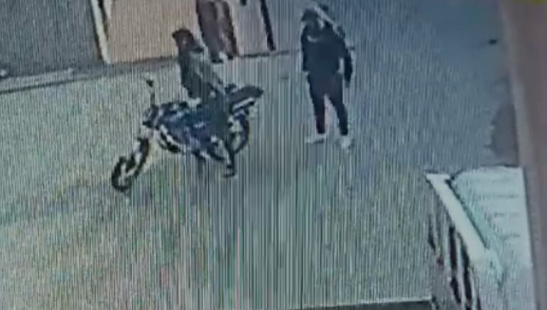 Una vez concretado el golpe, ambos delincuentes se disponen a abordar la motocicleta, que dejaron estacionada sobre la vereda de la distribuidora para escapar.