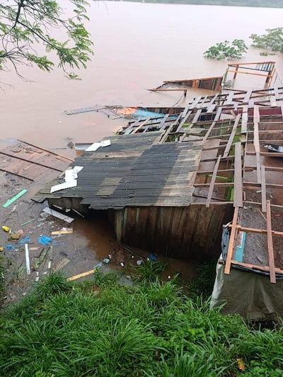 Estructura de madera dañada junto al río Paraná, rodeada de vegetación y desechos por inundación.