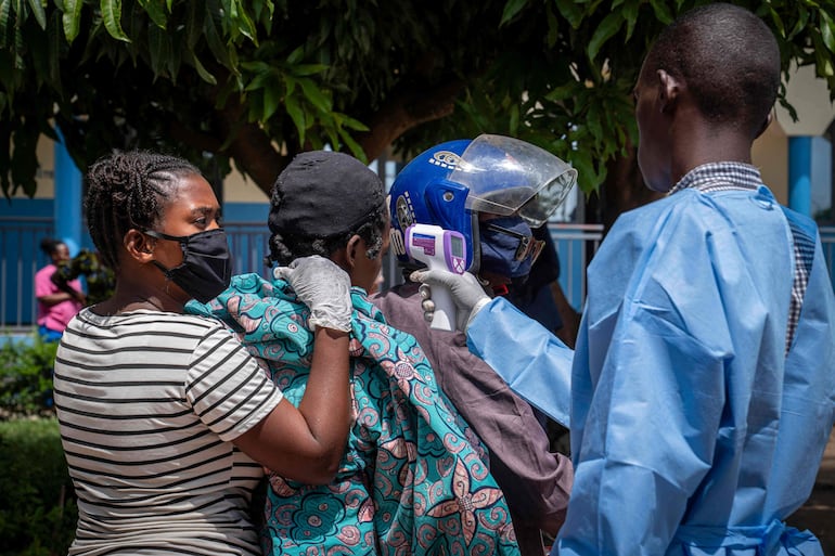 Un trabajador de la salud (der.) toma la temperatura de una paciente (2.ª izq.) sospechosa de tener ébola mientras es trasladada en mototaxi al Hospital Rwampara, en Ituri, en el este de la República Democrática del Congo, el 26 de mayo de 2026.
