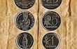 Monedas de 1, 5 y 10 guaraníes sobre fondo arrugado, con inscripciones que mencionan 'Alimentos para el mundo'.