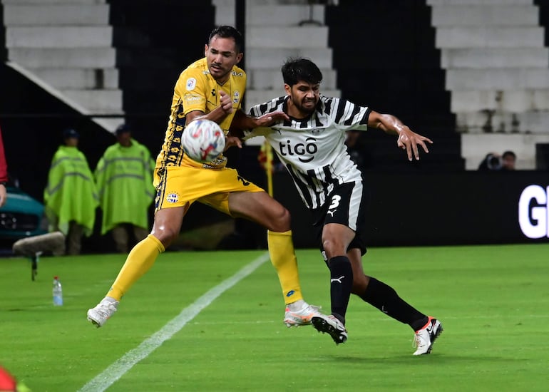 Clemantino González de Trinidense intenta bajar la pelota ante la embestida de Robert Rojas.