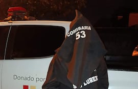 Persona arrestada con bolsa en la cabeza, sudadera negra 'COMISARIA 53', esposado frente a una camioneta de Itaipú Binacional.