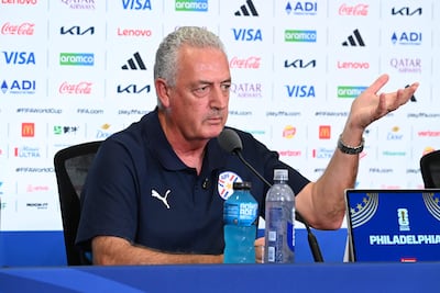 Gustavo Alfaro con camiseta oscura y escudo de la APF, gesticulando en una mesa de prensa rodeada de logotipos de patrocinadores.
