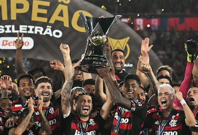Giorgian de Arrascaeta y Bruno Henrique, principales referentes del Flamengo, sostienen el trofeo de campeón conquistado por el club más popular del Brasil.