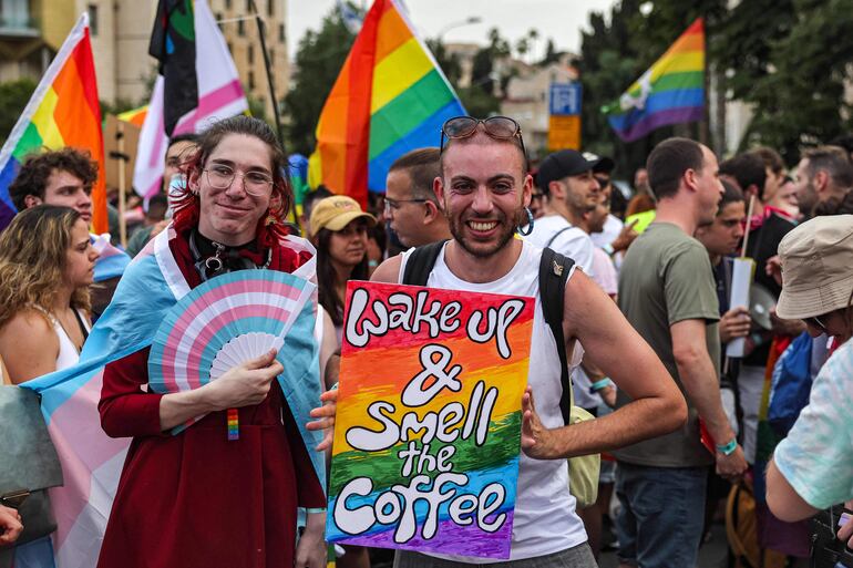 Contentos y con la bandera del orgullo gay y un abanico con los colores del movimiento transgénero, estos manifestantes participan de la marcha del orgullo gay en Jerusalén, Israel. 
