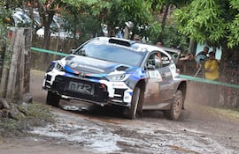Coche de rally Toyota avanzando en un terreno embarrado, levantando barro durante una carrera exigente.