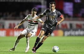 Enfrentamiento de experimentados, el liberteño Roque Santa Cruz se lleva el balón ante la persecución de Óscar, anoche en Brasil.