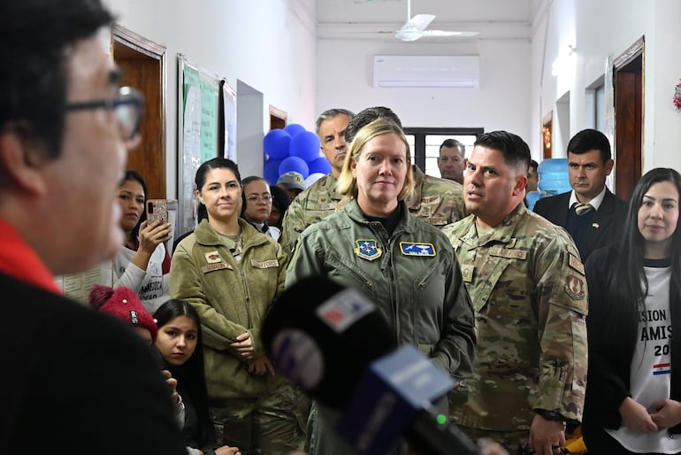 Mujeres y hombres en uniforme militar en evento formal, algunos sosteniendo micrófonos, con ambiente de atención médica.
