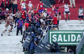 Hinchas de Cerro Porteño y agentes de la Policía se enfrentan durante el clásico del fútbol paraguayo, el domingo en el estadio Defensores del Chaco de Asunción.