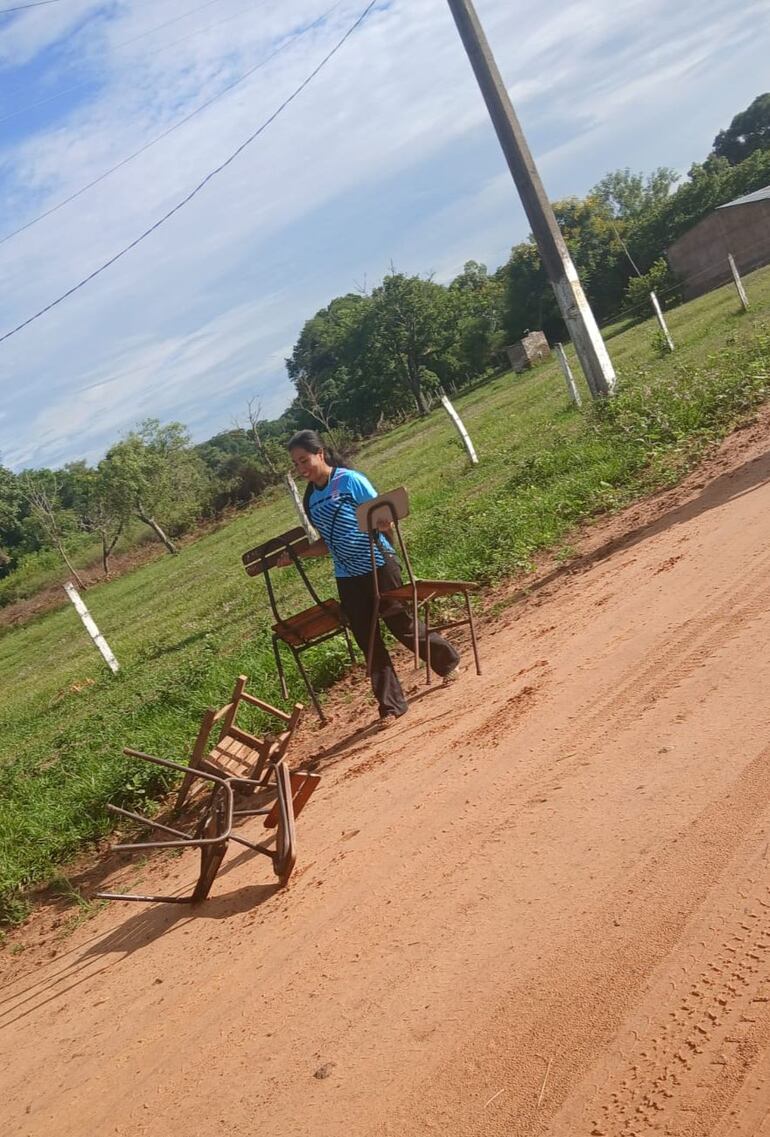 Los padres de los alumnos llevan a pie las sillas que utilizarán para dar clases en el oratorio. 