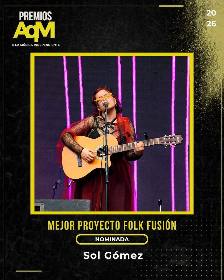 Sol Gómez canta con guitarra, luciendo gafas amarillas y vestuario oscuro con detalle rojo, en un ambiente festivo.