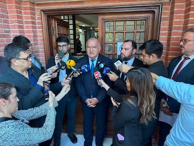Walter Santiago Laguardia en chaleco y corbata respondía preguntas de varios reporteros en un ambiente exterior.