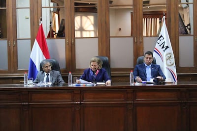 Diego Crispín Candia Melgarejo habla con documentos en mano, mientras Alicia Pucheta sonríe y escucha atenta, en ambiente institucional.