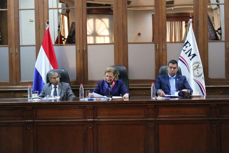 Diego Crispín Candia Melgarejo habla con documentos en mano, mientras Alicia Pucheta sonríe y escucha atenta, en ambiente institucional.