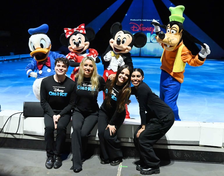 Cuatro jóvenes posan sonrientes junto a Mickey Mouse, Minnie Mouse, Donald Duck y Goofy en evento de 'Disney On Ice'.