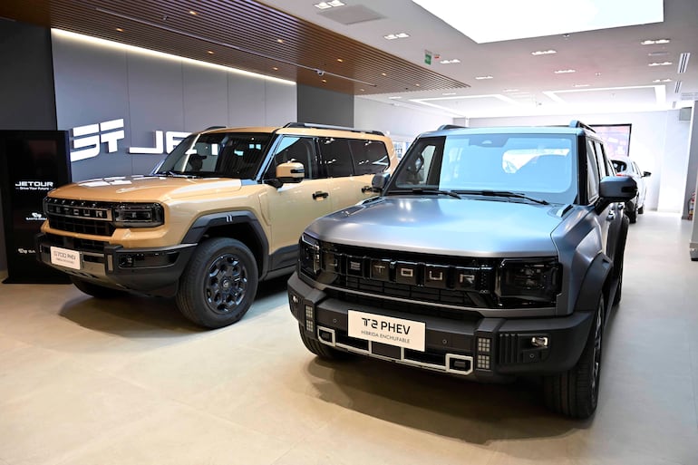 Dos SUV híbridos en exhibición, uno dorado y otro gris oscuro, en un ambiente moderno de concesionario JETOUR.