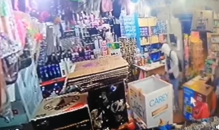 Uno de los delincuentes ingresa al local comercial para anunciar el asalto.