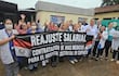 Grupo de médicos en uniforme sosteniendo pancarta que dice 'REAJUSTE SALARIAL' durante la protesta frente al hospital.