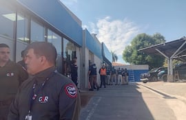 Grupo de seguridad GSR con uniformes oscuros, coordinan mientras un hombre con placa supervisa la situación en un edificio.