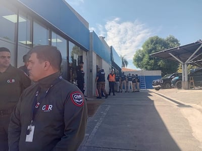 Grupo de seguridad GSR con uniformes oscuros, coordinan mientras un hombre con placa supervisa la situación en un edificio.