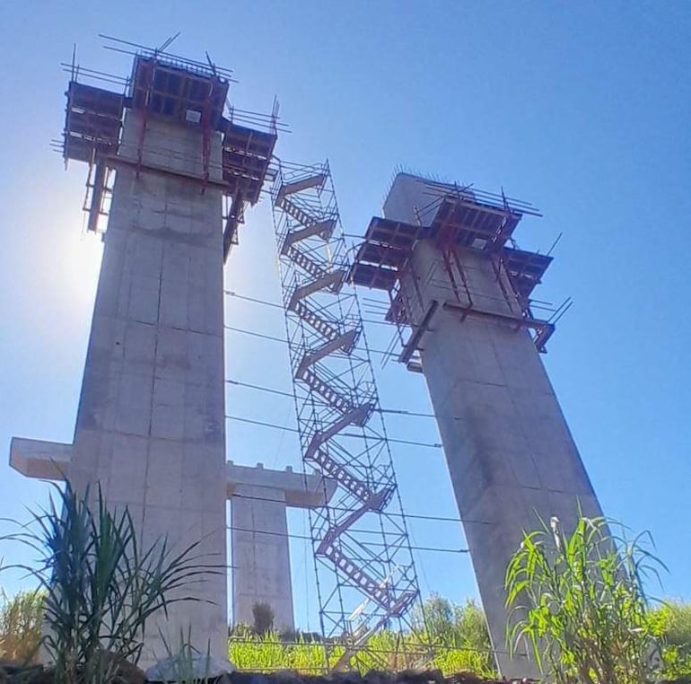 Torres de concreto en construcción bajo un cielo despejado, rodeadas de vegetación. Sin personas visibles en la imagen.