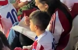 Madre e hijo repasan la lección durante la previa del juego entre Paraguay y Uruguay.