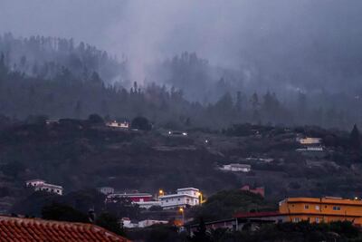 Una fotografía tomada cerca de Los Realejos, en la isla canaria de Tenerife muestra humo sobre las casas durante un incendio forestal que arrasa las áreas boscosas que rodean el parque natural del volcán Teide.