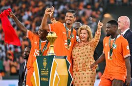 El delantero de Costa de Marfil #22 Sebastien Haller (CL) posa con la Primera Dama de Costa de Marfil Dominique Ouattara (CR) después de ganar al final del partido final de fútbol de la Copa Africana de Naciones (CAN) 2024 entre Costa de Marfil y Nigeria en el Estadio Olímpico Alassane Ouattara en Ebimpe, Abidjan, el 11 de febrero de 2024. (Foto de Sia KAMBOU / AFP)