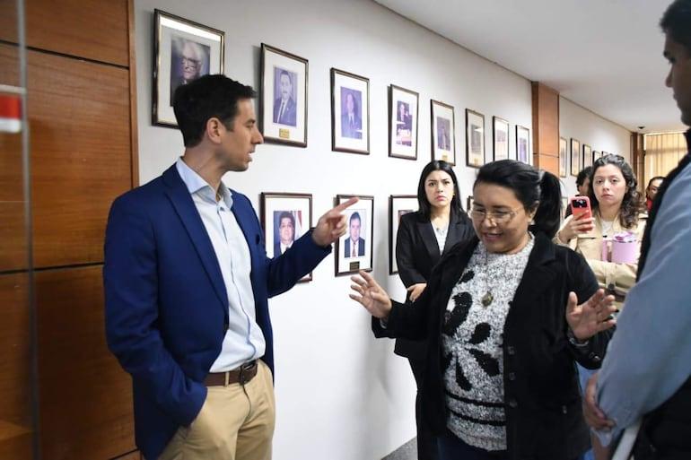 Alvaro Grau en chaqueta azul habla con mujer de blusa negra, mientras otras dos funcionarias observan en un edificio institucional.