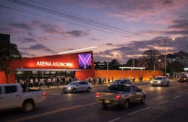 Vista exterior de la Arena Asunción con letrero luminoso, fila de personas vestidas informalmente, al atardecer.
