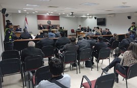 VDB Sala de audiencias con jueces en panel y público presente, ambiente formal y bandera de Paraguay visible.