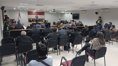 VDB Sala de audiencias con jueces en panel y público presente, ambiente formal y bandera de Paraguay visible.