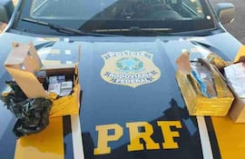 Vehículo policial de Brasil con emblema visible, rodeado de cajas abiertas que contienen paquetes sospechosos.