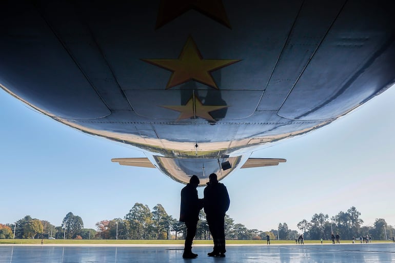  Personas observan un avión plateado de Aerolíneas Argentinas en un hangar este jueves, en el Aeropuerto Internacional de Ezeiza en José María Ezeiza (Argentina). La línea aérea estatal Aerolíneas Argentinas presentó el avión que llevará a la selección argentina de fútbol al Mundial 2026, con un diseño que incorpora la camiseta número 10 del capitán y figura del equipo, Lionel Messi. EFE/ Juan Ignacio Roncoroni
