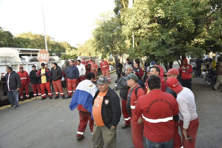 Un grupo de personas en uniforme rojo, algunos con etiquetas de 'Municipalidad de Asunción', se congrega en la vía pública en un ambiente de protesta.