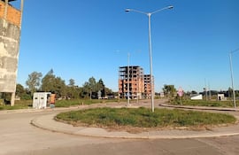 Construcción inacabada de gran edificio en un área urbana con cielo despejado y rotonda con césped.