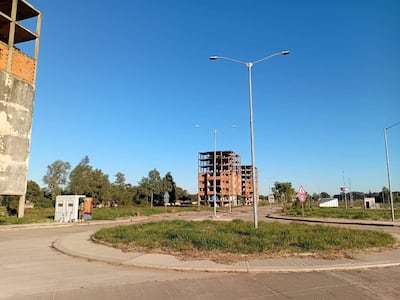 Construcción inacabada de gran edificio en un área urbana con cielo despejado y rotonda con césped.
