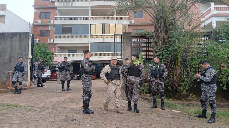 Grupo de siete personas en uniformes de seguridad, encabezados por un hombre con sombrero, frente a un edificio de varios pisos.