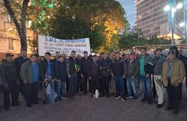 Grupo de personas con ropa oscura sosteniendo un cartel con '1. D.I. DE INFANTERÍA' en un espacio público.