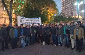Grupo de personas con ropa oscura sosteniendo un cartel con '1. D.I. DE INFANTERÍA' en un espacio público.