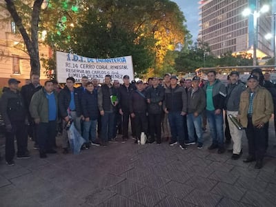 Grupo de personas con ropa oscura sosteniendo un cartel con '1. D.I. DE INFANTERÍA' en un espacio público.