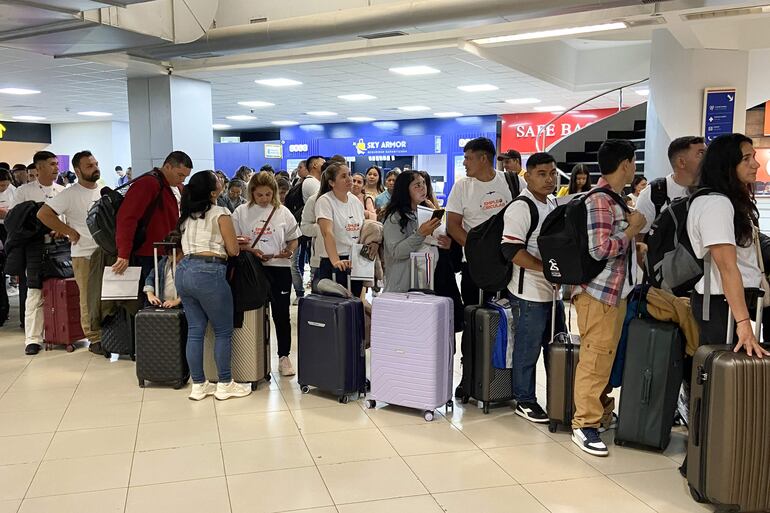 Trabajadores esperan a una fila este lunes, en el Aeropuerto Internacional Silvio Pettirossi en Luque (Paraguay). 