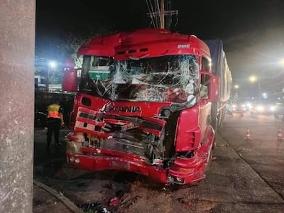 Camión Scania con frontal dañado y trabajador de emergencias evaluando la situación en una carretera oscura.