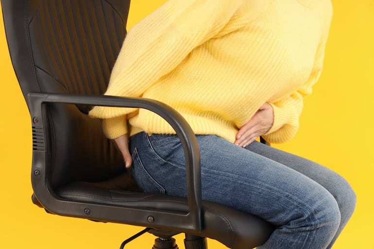 Mujer con dolor al sentarse, concepto de hemorroides.