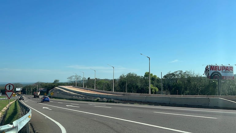Carretera con señalización y un cartel publicitario de NEUPAR en un día soleado, sin personas visibles.
