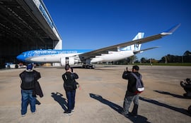 Personas observan un avión plateado de Aerolíneas Argentinas ingresando a un hangar este jueves, en el Aeropuerto Internacional de Ezeiza en José María Ezeiza (Argentina). La línea aérea estatal Aerolíneas Argentinas presentó el avión que llevará a la selección argentina de fútbol al Mundial 2026, con un diseño que incorpora la camiseta número 10 del capitán y figura del equipo, Lionel Messi. EFE/ Juan Ignacio Roncoroni